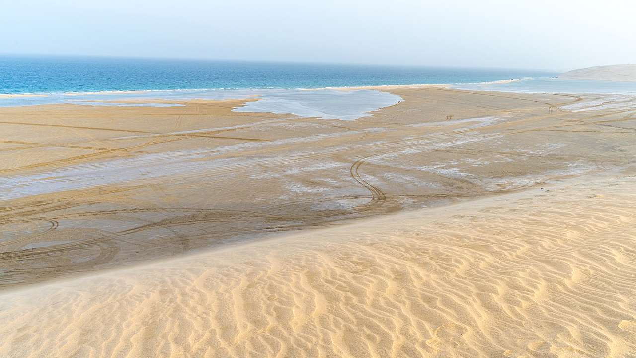 White sand dunes meet the vast, blue sea