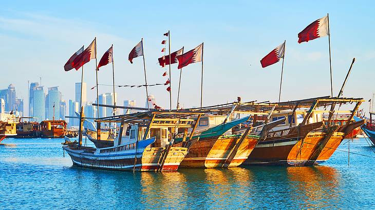Traditional wooden boats with flags on top moored in blue water