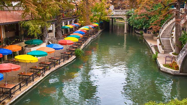 A body of water surrounded by a walking path with multi-colored umbrellas