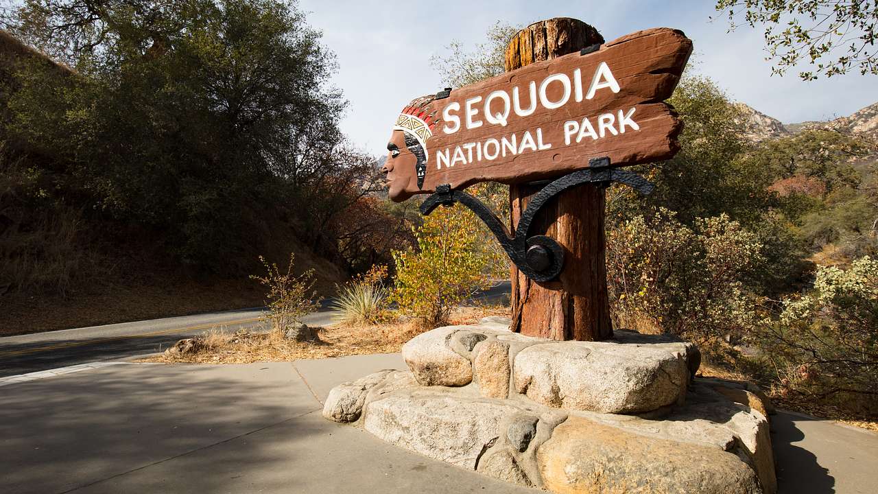 A wooden sign titled Sequoia National Park on a two-tier platform made of rocks