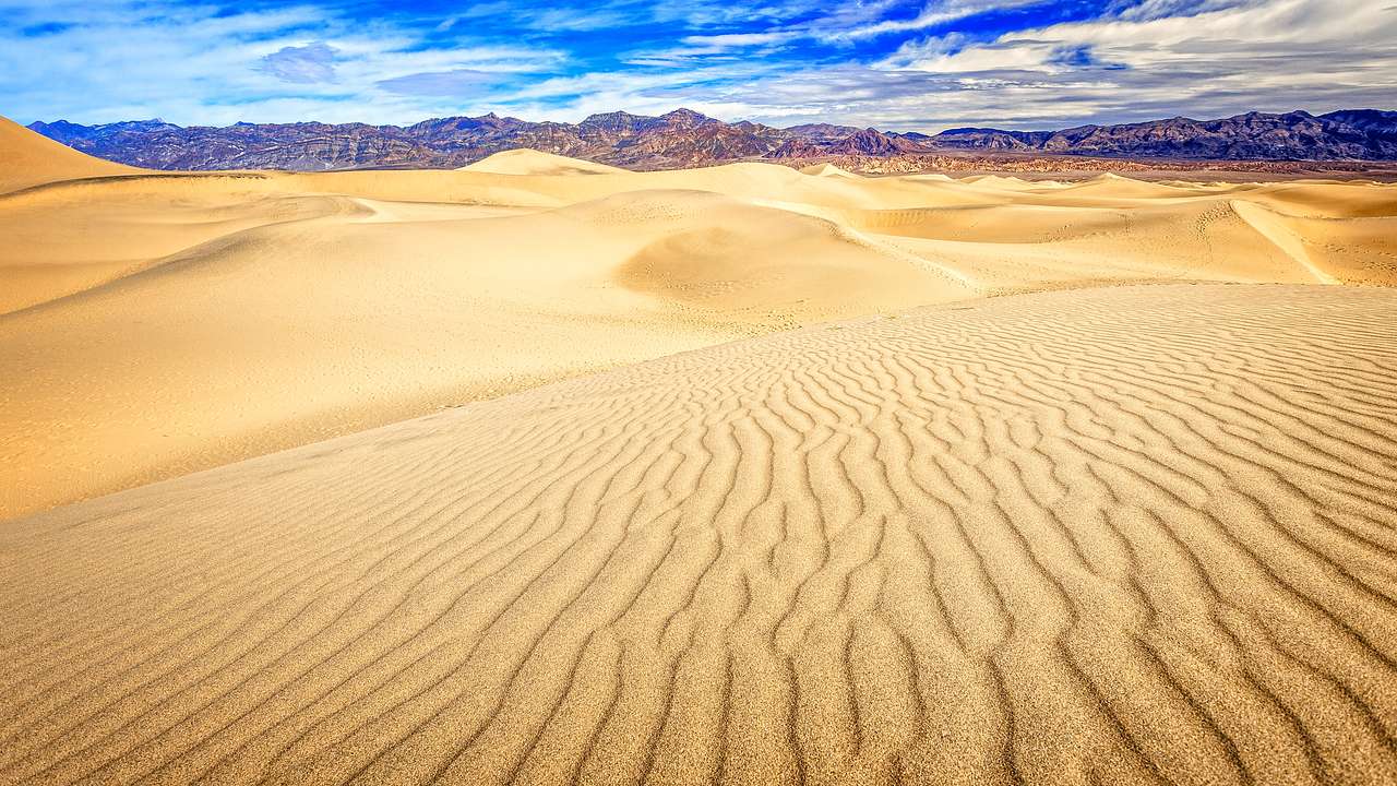 Ripples on the sand in a desert valley with mountains in the background
