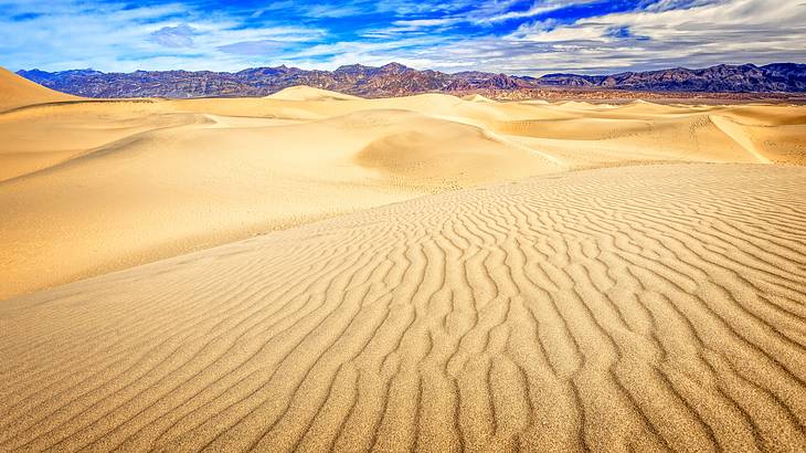 Ripples on the sand in a desert valley with mountains in the background