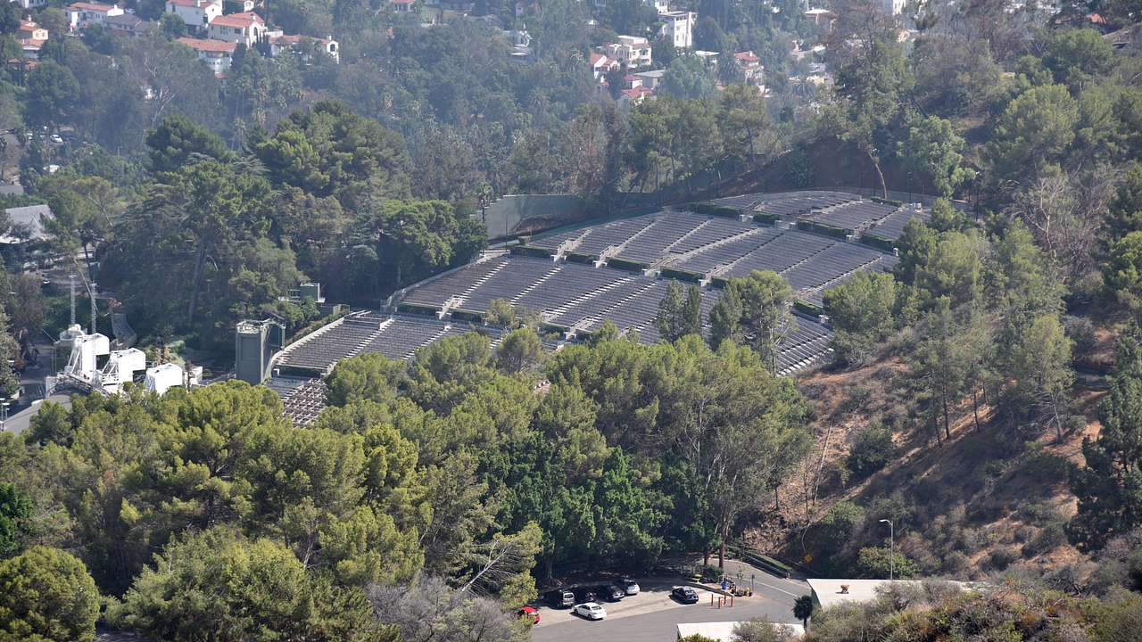 Aerial shot of an amphitheater surrounded by greenery, buildings and houses
