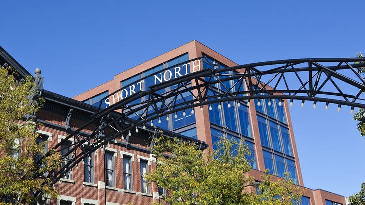 An iron sign that says "Short North" next to red brick buildings and trees