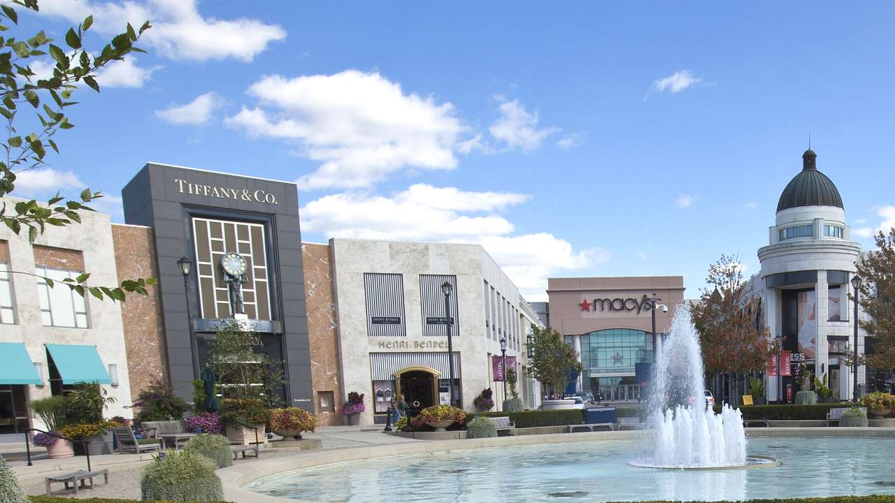 A Tiffany's shop and Macy's store next to a large water fountain and other buildings