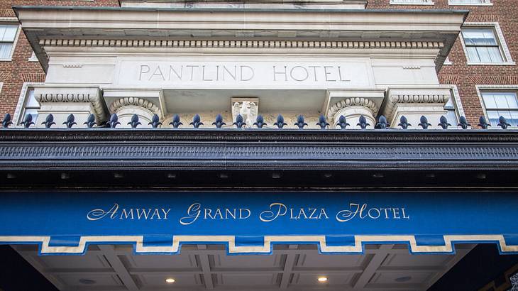 The exterior of a hotel with a blue sign that says "Amway Grand Plaza Hotel"