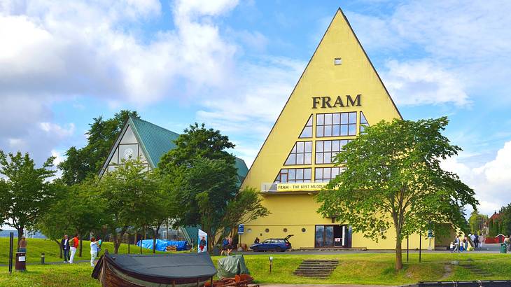 A yellow triangular building with a sign that says "Fram" next to green trees