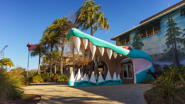 Alligator head building entrance, with trees behind, under a clear blue sky