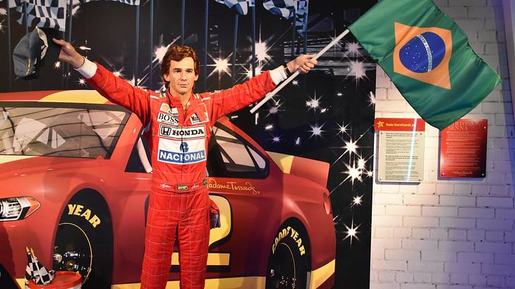 A wax figure of a Formula One driver carrying a green, yellow, and blue flag
