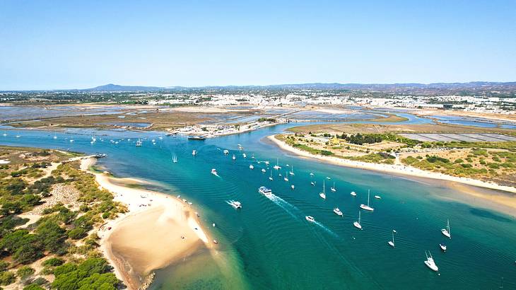 A view of an island with boats on the water and sandy beaches with greenery A view of an island with boats on the water and sandy beaches with greenery