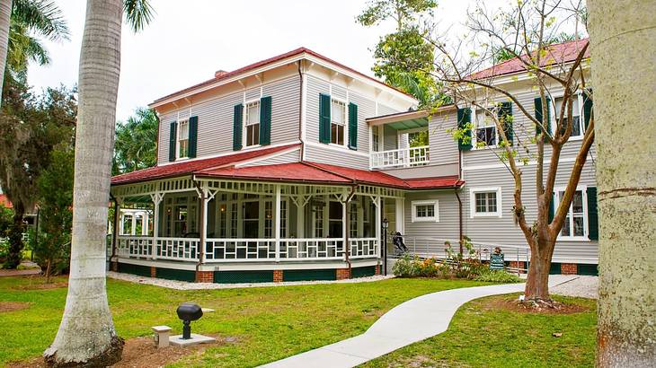 A pathway between green grass to a vernacular-style house with a red roof