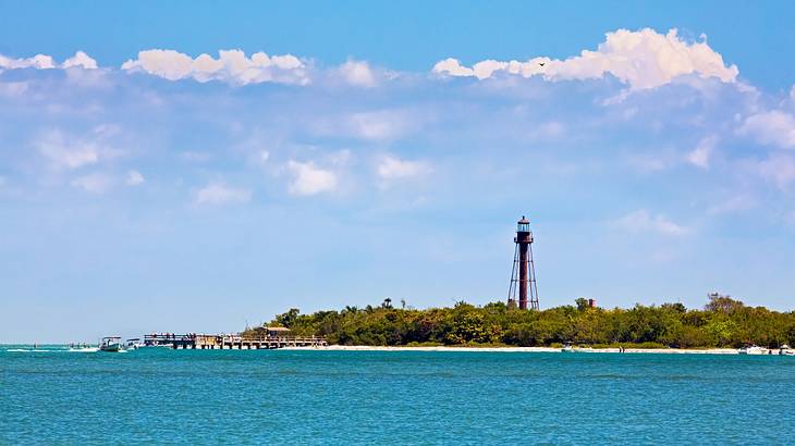 Blue ocean water next to an island with greenery and a lighthouse