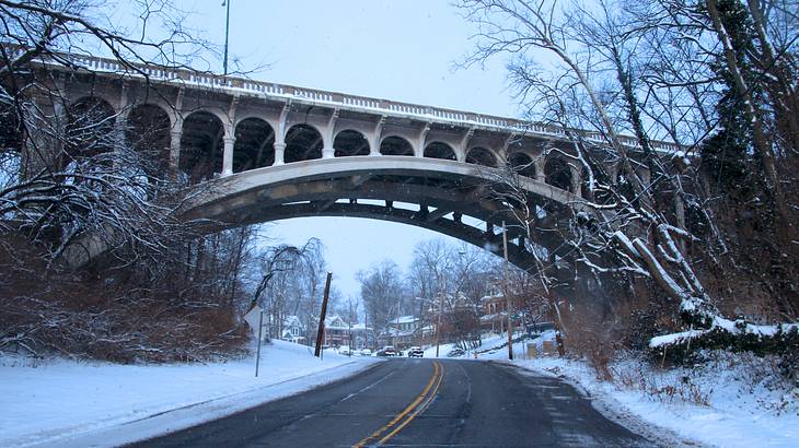 A snow-lined road spanned by a bridge