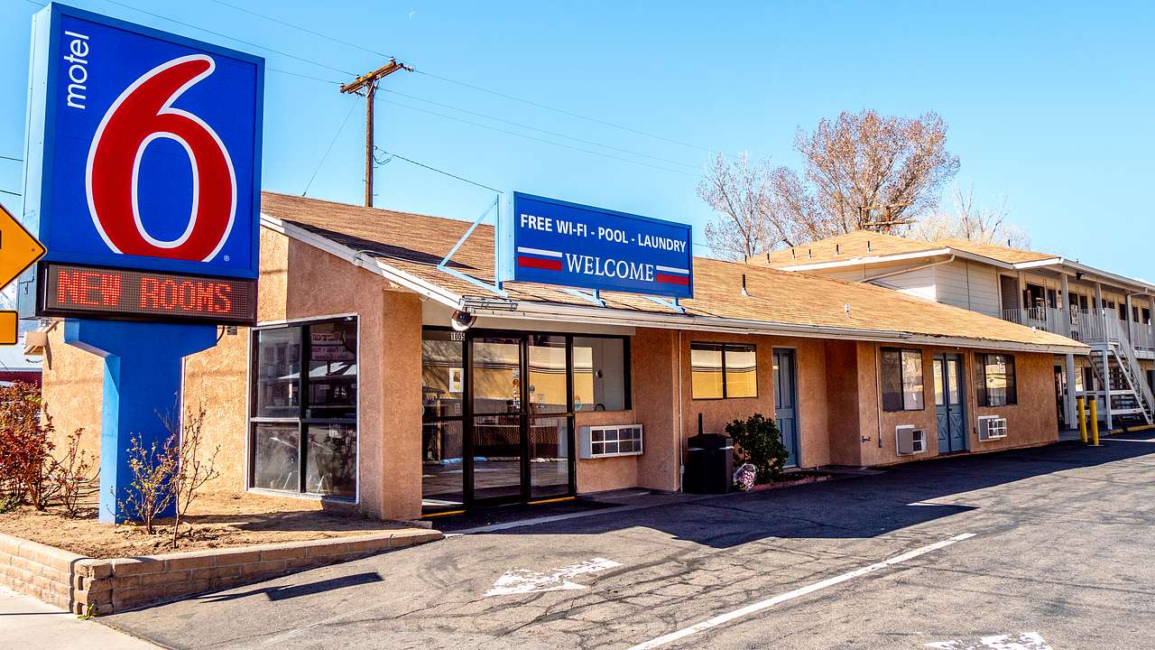 A low building with a blue and red "Motel 6" sign next to a blue sky