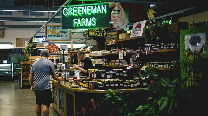 A person buying something from an indoor market stall and a "Greeneman Farms" sign