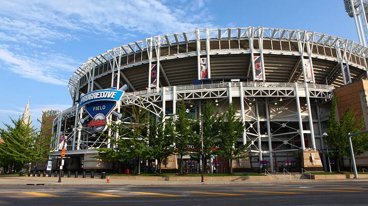 A baseball stadium with a sign that says "Progressive Field" next to a road and trees