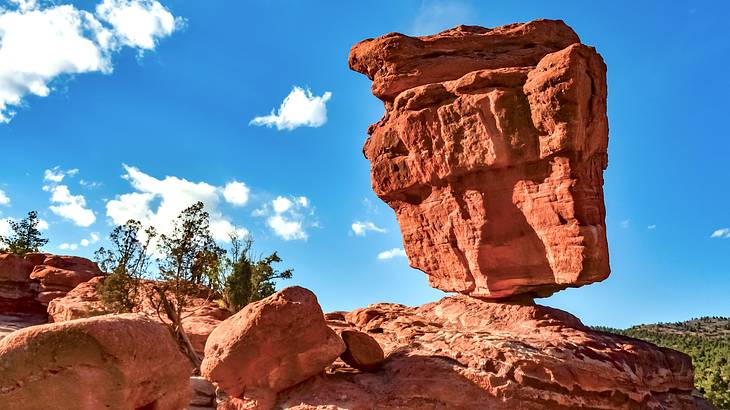 A large red rock formation with another huge rock balancing on one edge on top of it