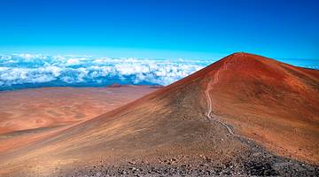 A barren red volcano in the foreground with clouds and a blue sky above