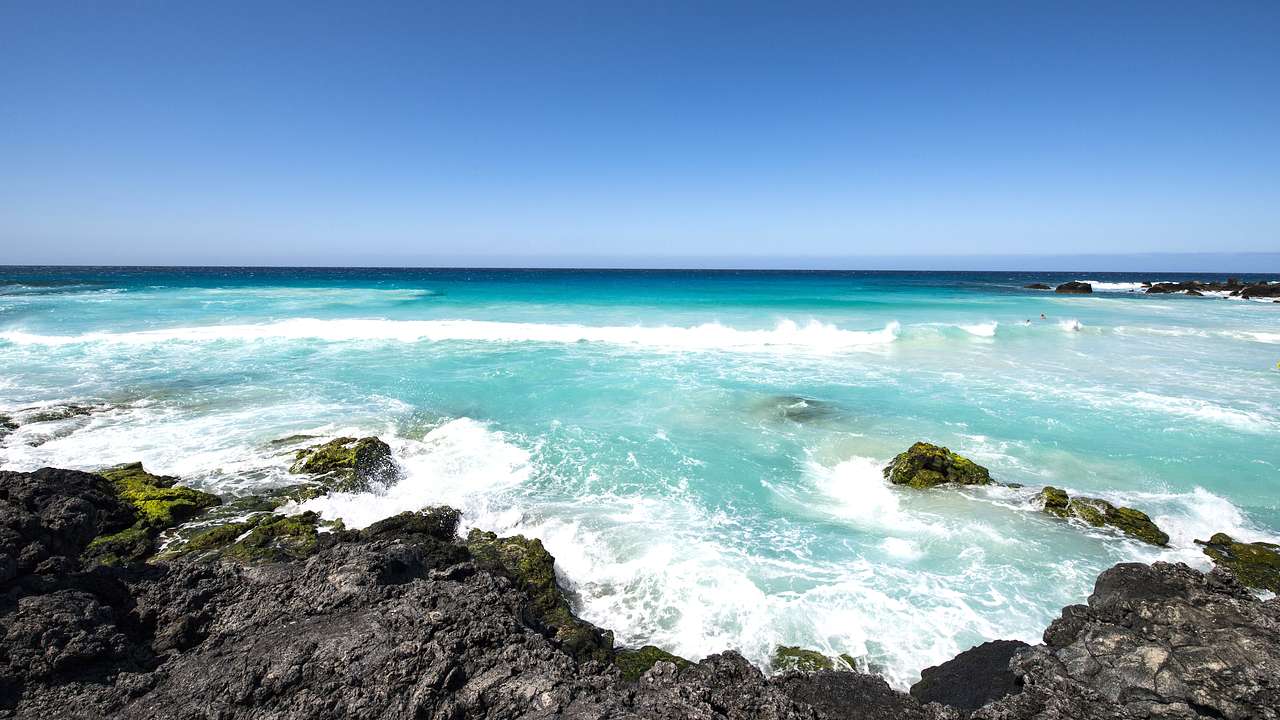 Turquoise water crashing on white sand and rocks on the beach