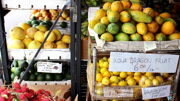 A shop with a variety fruits piled in separate boxes with price cards in front