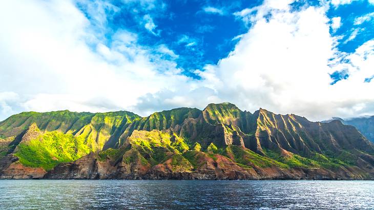 Deep blue ocean and green mountain under a cloudy sky