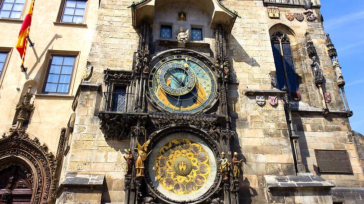 Old building tower with clocks and flags on it from below