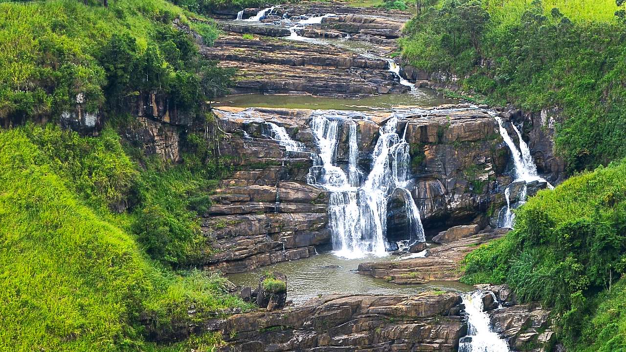 Many small waterfalls falling down rock into water below