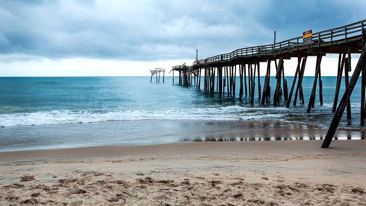 The iconic fragmented Frisco pier, over a beach under cloudy skies