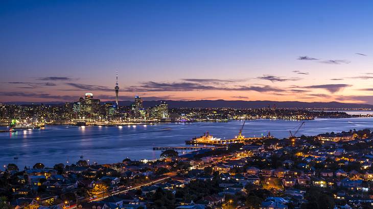 The sun setting over a city skyline and water from a mountain top