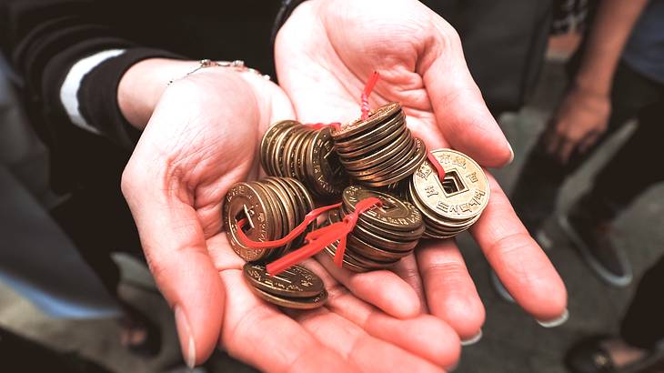 Gold coins on a red twist tie in hands from above