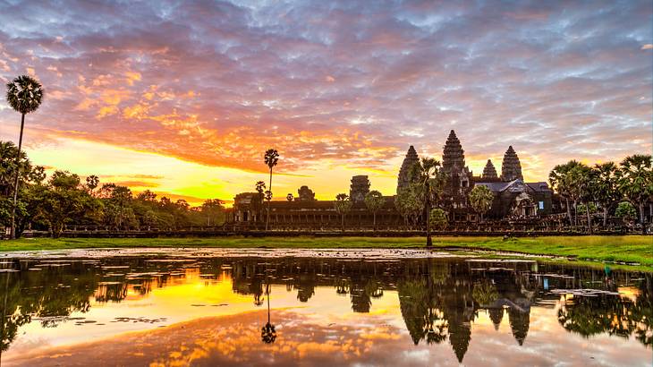 Temple and tree silhouettes reflected on water at sunrise