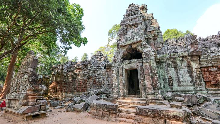 The exterior of an ancient temple next to green trees on a sunny day