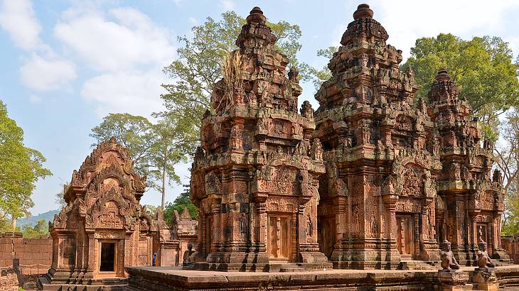 Small reddish temples beside each other against a partly cloudy sky