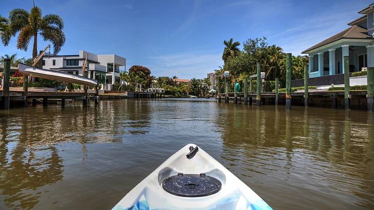 Looking towards the tip of a kayak on a lake with wooden docks and palm trees around Looking towards the tip of a kayak on a lake with wooden docks and palm trees around