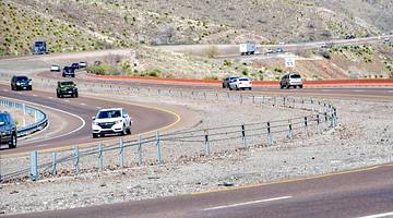 Winding roads lined with metal fencing, with cars traveling in both directions