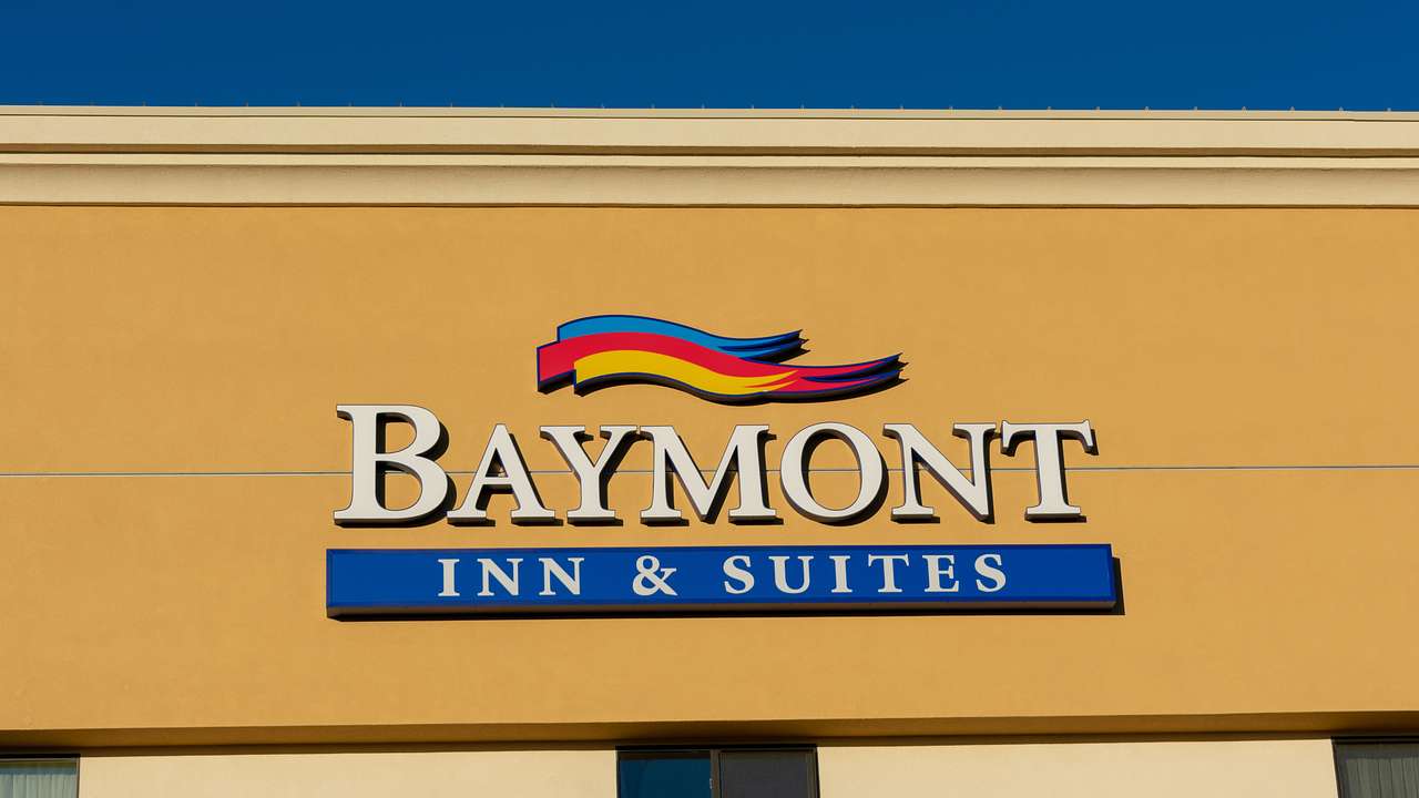A sign on a yellow building that says "Baymont Inn & Suites" against a blue sky