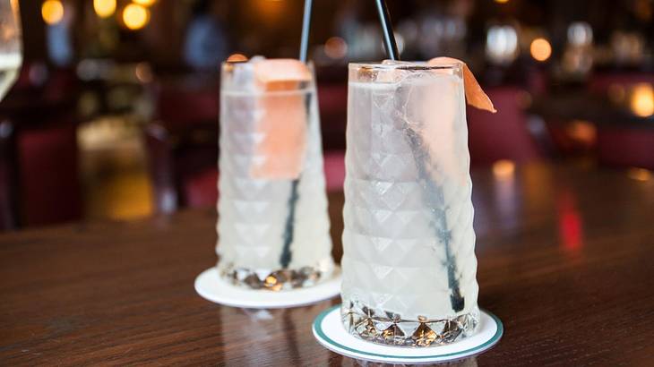 Two cocktails on a table in a bar