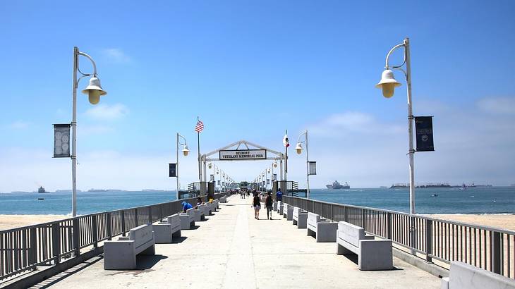A pier with benches and lamps on it and the ocean on either side