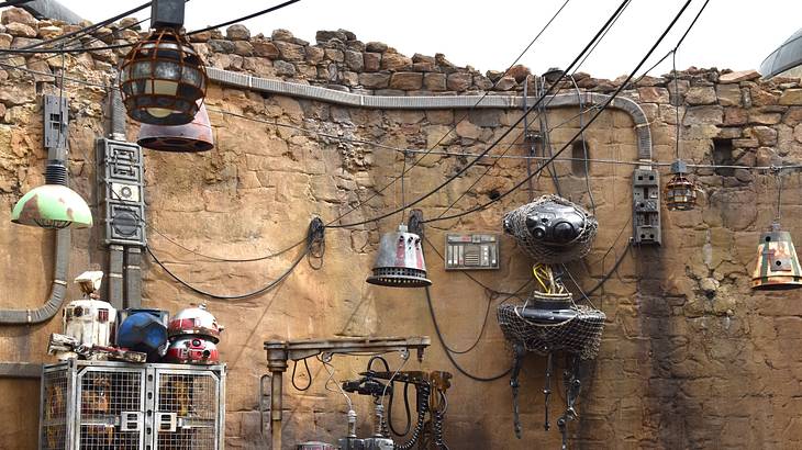 A stone wall with wires and metal gadgets attached to it and more wires overhead A stone wall with wires and metal gadgets attached to it and more wires overhead