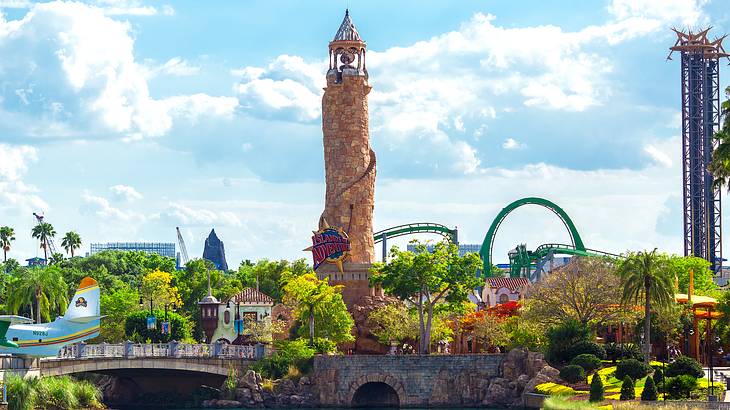 An orange lighthouse towering over a body of water, a bridge, and an amusement park An orange lighthouse towering over a body of water, a bridge, and an amusement park