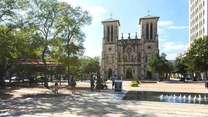 Looking across a plaza with trees at a gothic-style cathedral with crosses on top Looking across a plaza with trees at a gothic-style cathedral with crosses on top
