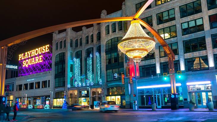 A street at night with a neon sign saying "Playhouse Square" and a chandelier