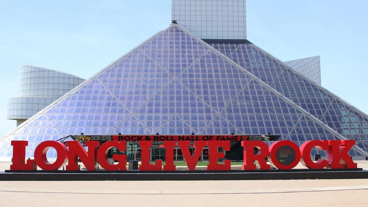 A glass pyramid building with a red "Long Live Rock" sign in front of it