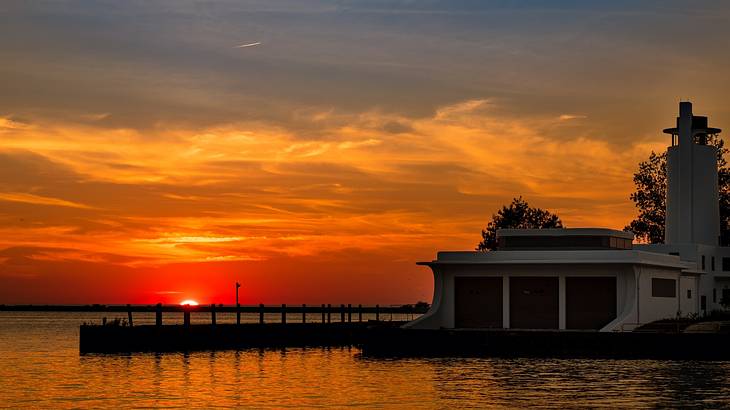 A white coast guard station with a small dock overlooking a lake during sunset