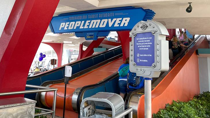 Blue and red covered escalators with a blue sign above that says "PEOPLEMOVER"