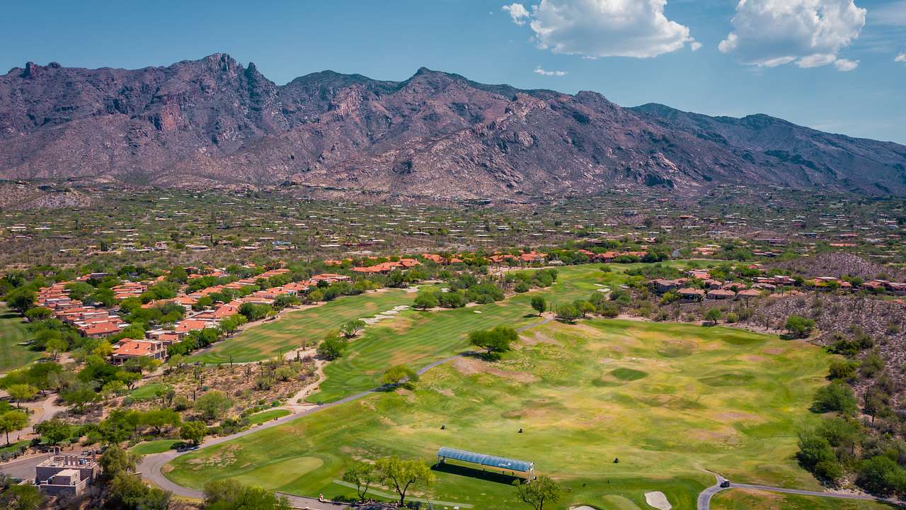 An aerial view of a golf course with a mountain range in the back