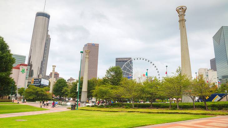 A park with a Ferris wheel and structures at the back with a carpet of grass in front