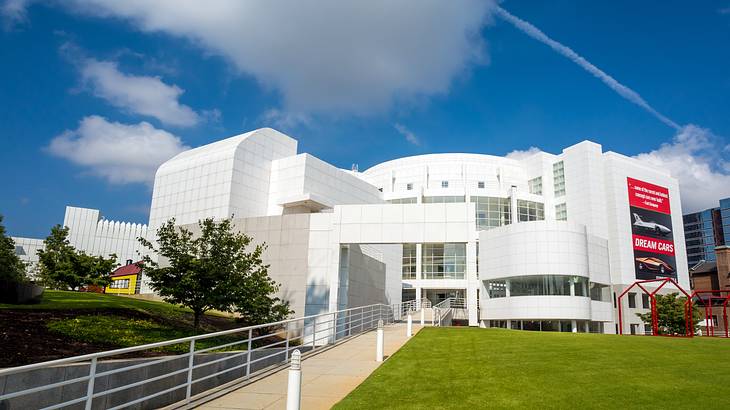 A modern white building next to the grass and a path on a sunny day