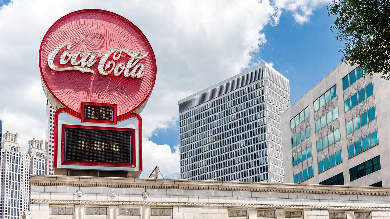 A round red sign that says "Coca-Cola" on top of a white stone building