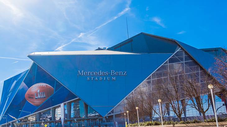 A modern building with a sign that says "Mercedes-Benz Stadium" on a sunny day